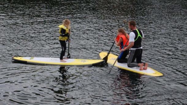 Tre mennesker på stand up paddle boards midt i vandet.