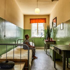 Pige sidder på en seng i en gammel celle på forsorgsmuseet i Svendborg.