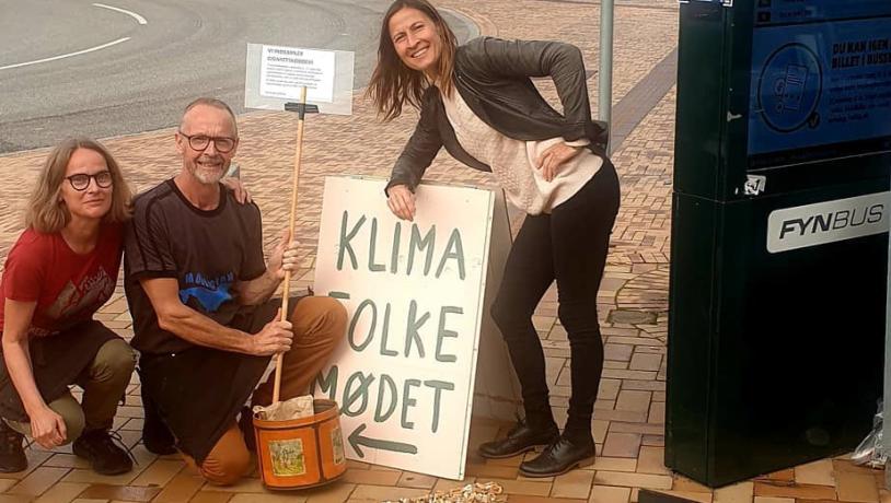 Stationen Kaffebar engagerer sig, hver gang der er store events i Middelfart - her sidder 3 mennesker ved et skilt i forbindelse med Klimafolkemødet.