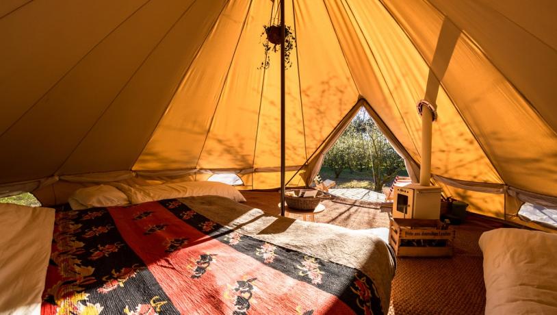 Hyggeligt glampingtelt set indefra i et varmt lys.