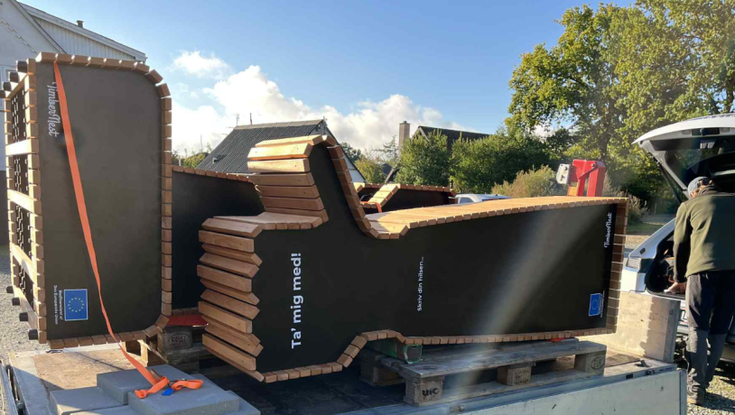 Blafferbænk med teksten "Ta' mig med!" på vej ned fra en trailer