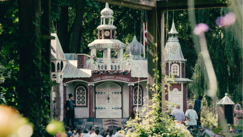 En scene formet som et eventyrslot i en grøn park bliver brugt som kulisse til en parade omhandlede eventyrforfatteren fra Odense, H. C. Andersen.