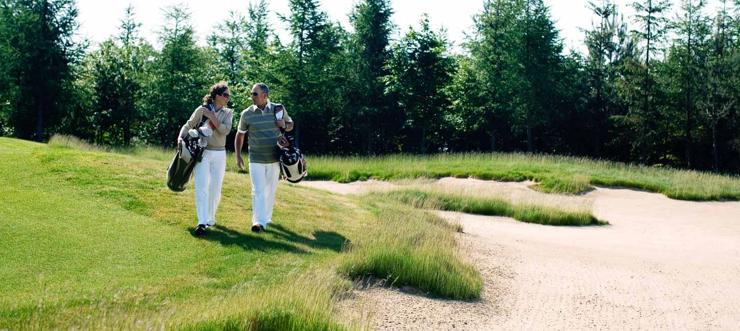 To golfspillere går tæt sammen og snakker på golfbane.