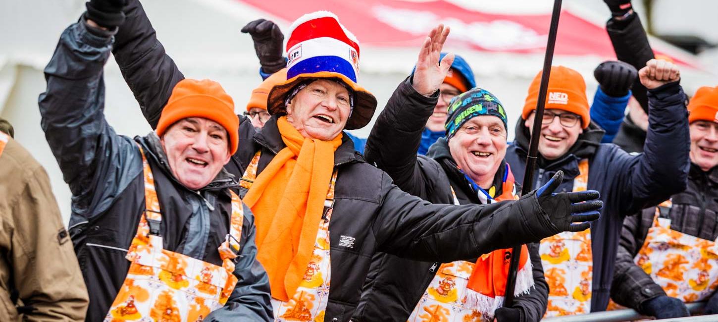 Cyklecrossfans til cykelevent i Bogense på Fyn står påklædte i orange farver og med hatte på.