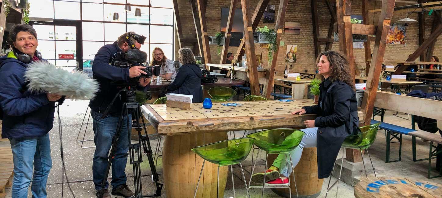Et lille hold interviewer en person ved et bord på et streetfood-marked.