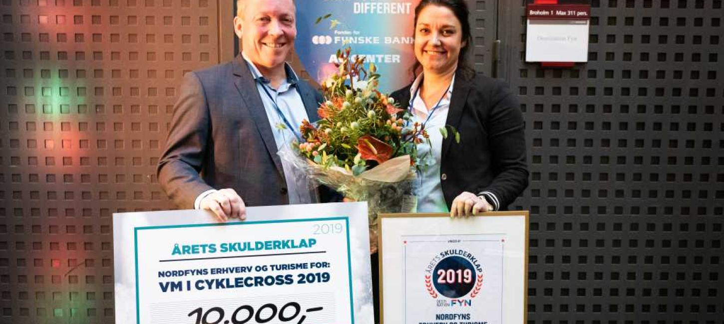 To personer på en scene, der har fået overrakt et gavekort på 10.000 kr. for Årets Skulderklap 2019