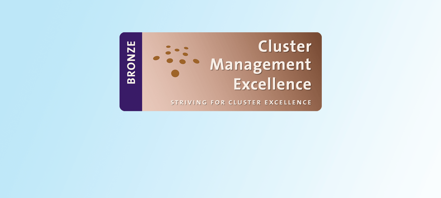 Bronzefarvet plastikkort med teksten Cluster Management Excellence på himmelblå baggrund.