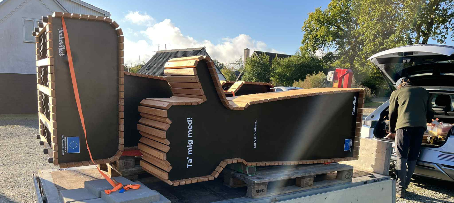 Blafferbænk med teksten "Ta' mig med!" på vej ned fra en trailer