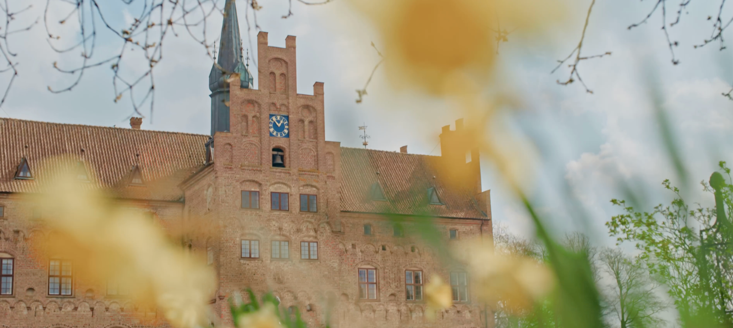 Egeskovs facade med påskeliljer i forgrunden