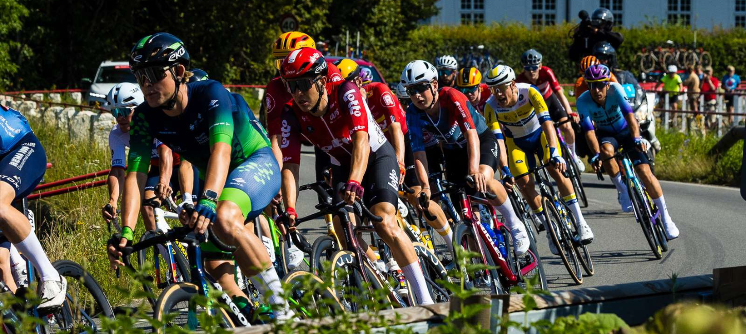 Cykelryttere på vej rundt i sving med tilskuere i baggrunden