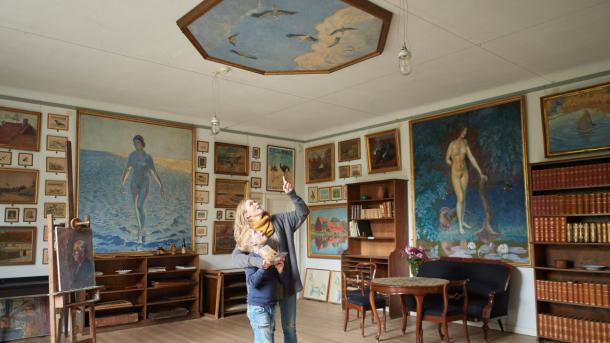 Mor og søn kigger på loftmaleri på Johannes Larsen Museet. De er omgivet af malerier lavet af Johannes Larsen