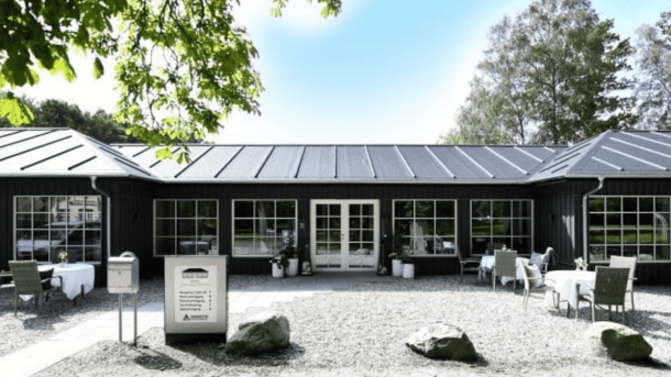 Et sortmalet hotel beliggende i en skov med grønne træer