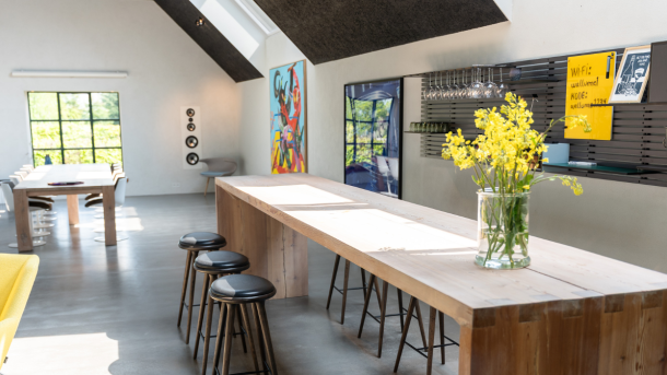 Lyst mødelokale med højt plankebord og barstole og et mødebord