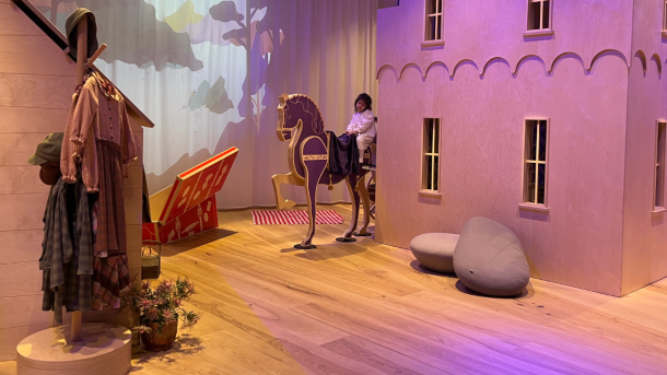 En lille pige sidder på en legetøjshest i Ville Vau, et børneunivers i H. C. Andersens hus i Odense.
