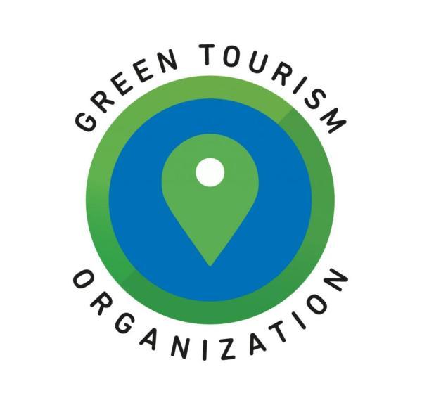 Cirkelrundt grønt og blåt logo med en grøn placeringsmarkør og teksten GREEN TOURISM ORGANIZATION.