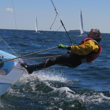Sejler hænger vandret på ydersiden af en contender-båd på havet.