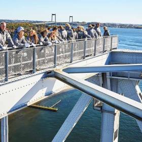 En flok mennesker på bridgewalking på den gamle Lillebæltsbro. Den nye Lillebæltsbro anes i baggrunden.