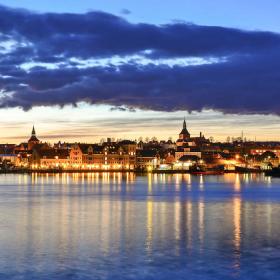 Udsigt over Svendborg Havn under en stor, mørkeblå sky med hyggelige lys fra byen.
