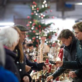 Mennesker, der står og kigger på julesager i boder ved julemarked.