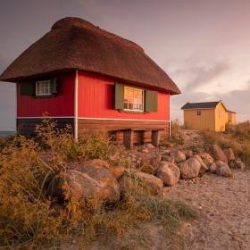 Et rødt og et gult badehus i pink solnedgang ved Eriks Hale ved Marstal, Ærø.