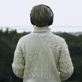 Person, der kigger ud over naturen ses bagfra med høretelefoner på