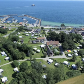Færgegårdens Camping ses oppe fra i droneperspektiv. Man kan også se vandet og naturen.