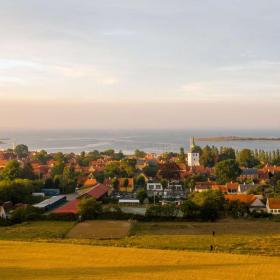 Landskabsbillede af Ærøskøbing med blå himmel og gul rapsmark.