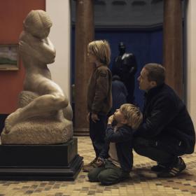 Far og to små drenge kigger på en skulptur på Faaborg Museum