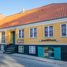 Gul bygning med sort sokkel og rødt tegltag. Skilt på bygningen, hvor der står "Søfartsmuseum".