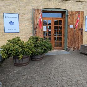 Indgang til Hørvævsmuseet. Foran indgangspartet ses to trækrukker med rododendron.