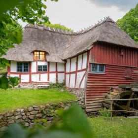 Vandmølle i miljø. Møllehuset er i rødt og hvidt bindingsværk.