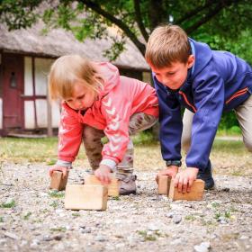 To børn leger med træklodser på jorden.
