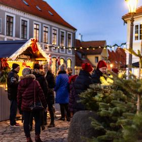 En flok mennesker, der står i en lille by ved en julebod, der sælger glögg 