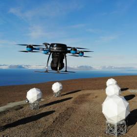 Drone, der flyver hen over nogle hvide elementer op mod en blå himmel