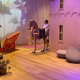 En lille pige sidder på en legetøjshest i Ville Vau, et børneunivers i H. C. Andersens hus i Odense. 