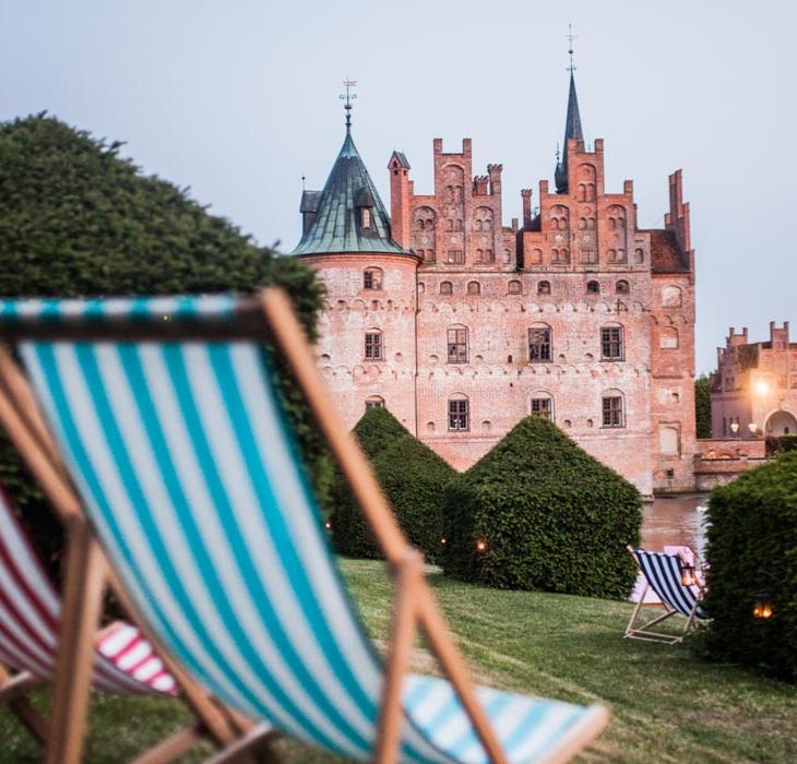 To af de klassiske stribede strand-liggestole i forgrunden - Egeskov Slot i baggrunden.