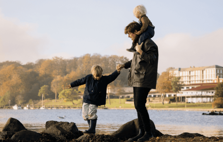 Børnefamilie ved Christiansminde Strand i Svendborg en efterårsdag med efterårstræer i baggrunden